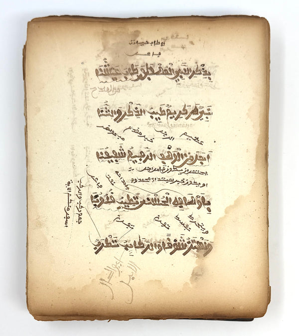 Arabic manuscript leaf with large poetic lines and smaller interlinear and marginal annotations.