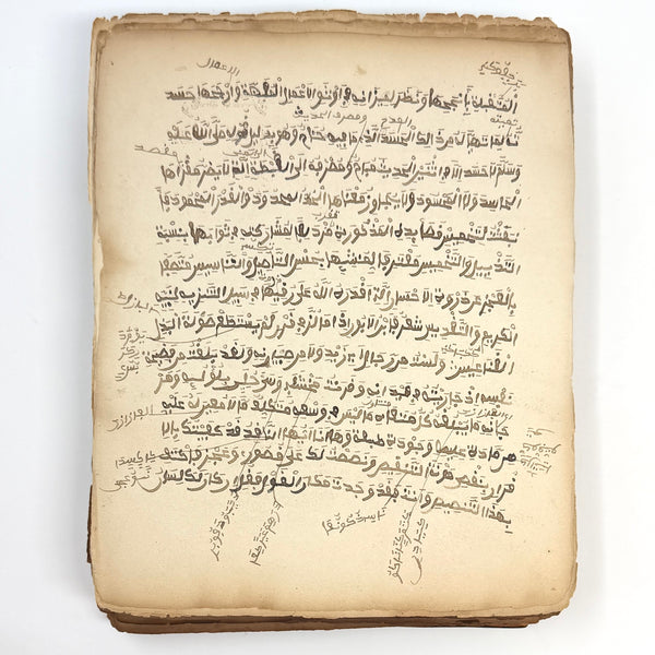 Arabic prose manuscript leaf in brown ink with marginal notes and toned paper edges.