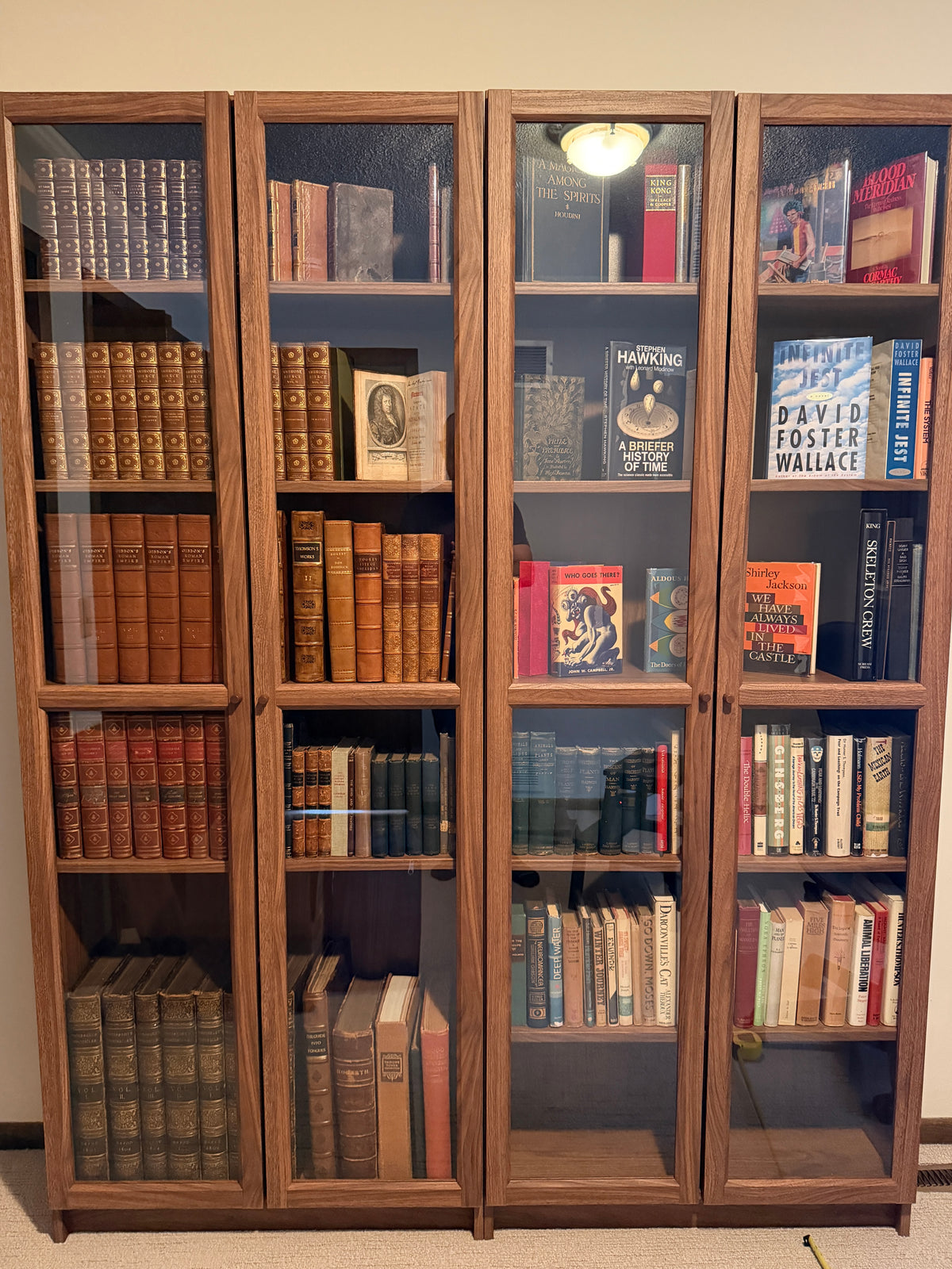 Rare and modern books displayed behind glass in a warm wooden cabinet